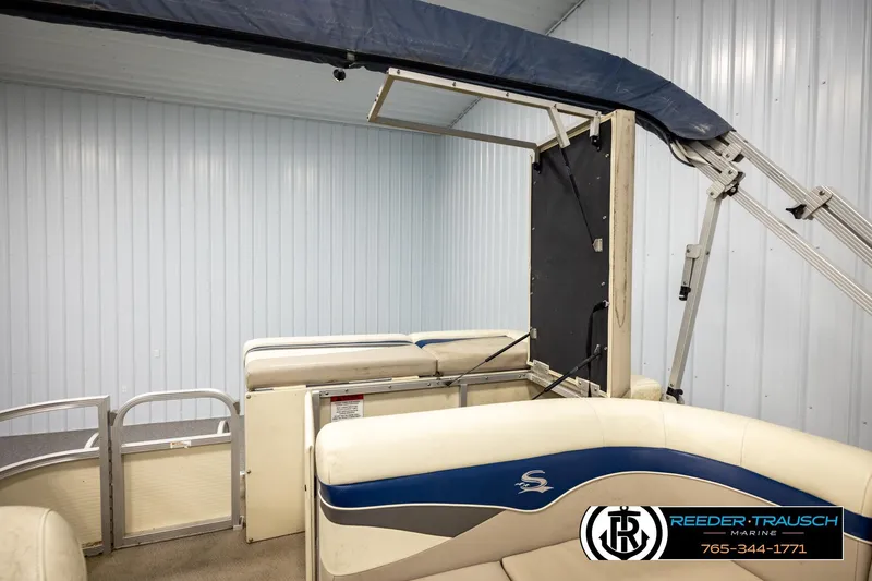 Slide: The Image of 2008 Sedona 20 CR boat interior with blue and white seating, under a metal canopy. - 23