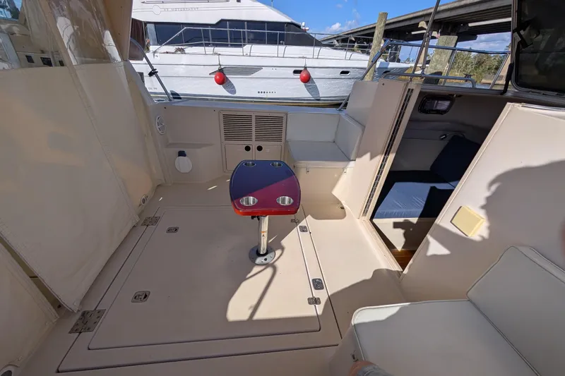 Slide: The Image of 2004 Albin 30 Family Cruiser interior with seating and table, docked near another boat. - 23