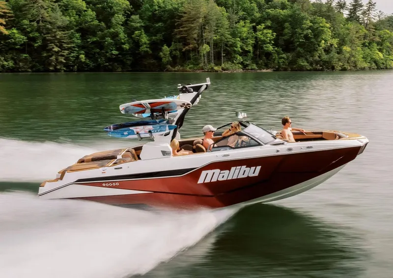 The Image of Manufacturer Provided Image: 2026 Malibu M230 boat cruising on a lake with lush green forest backdrop. - 0