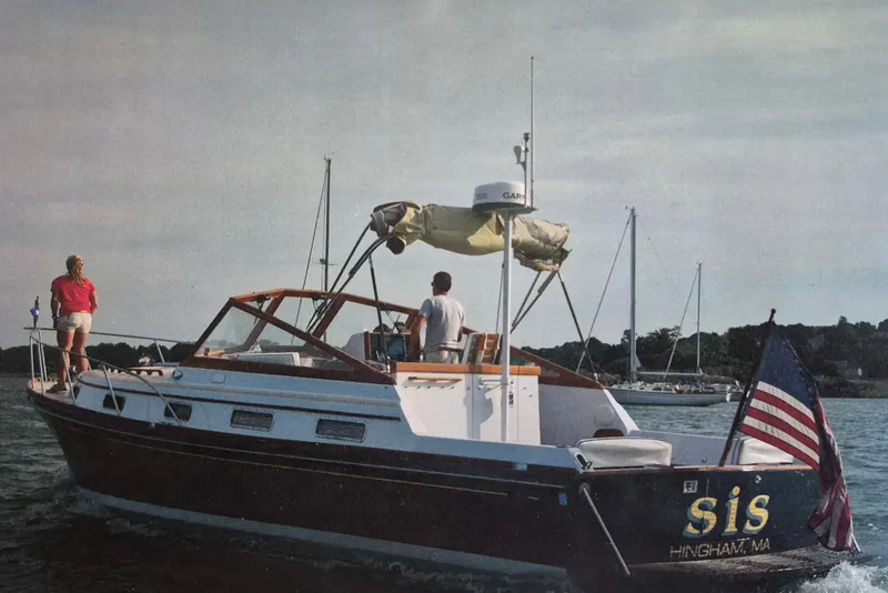 The Image of 1990 Little Harbor Express boat on water, American flag, two people onboard, scenic background. - 1