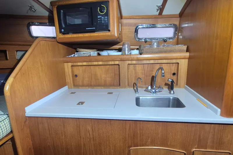 Slide: The Image of 1990 Little Harbor Express yacht kitchen with wooden cabinetry, sink, and microwave. - 15