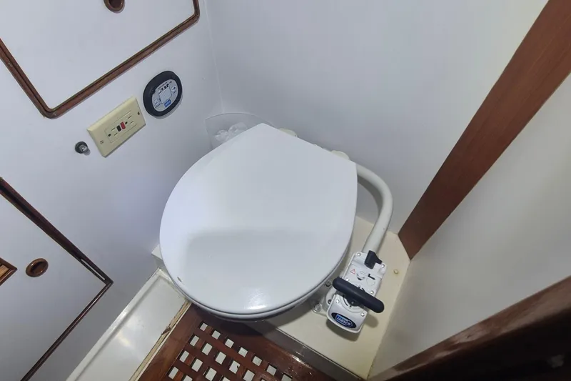 Slide: The Image of Marine toilet in 1990 Little Harbor Express boat bathroom, featuring wooden accents and control panel. - 27