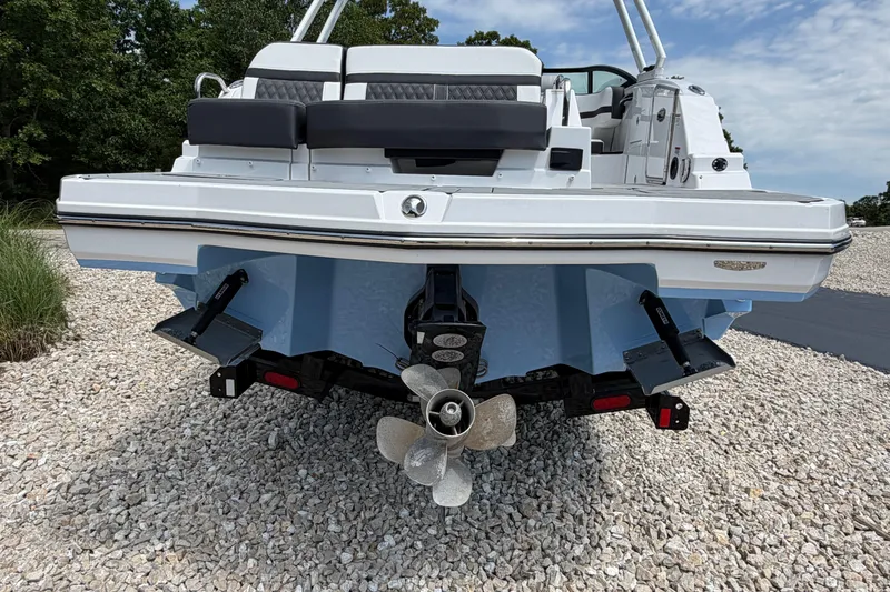 Slide: The Image of 2025 Monterey M6 boat rear view with propeller and seating, parked on gravel. - 4