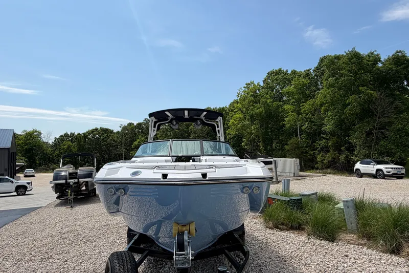 Slide: The Image of 2025 Monterey M6 boat on trailer, parked outdoors with trees and vehicles in the background. - 7
