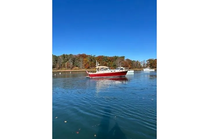Slide: The Image of 1998 Grand Banks 38 Eastbay EX boat on calm water, surrounded by autumn trees. - 23