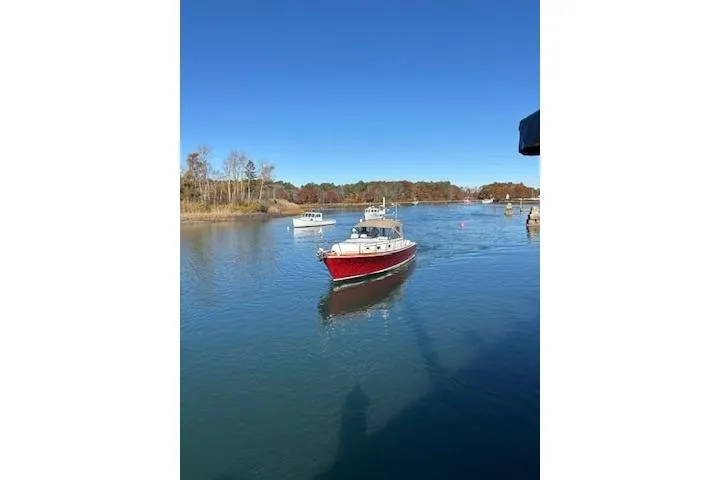 Slide: The Image of 1998 Grand Banks 38 Eastbay EX cruising on a serene river under a clear blue sky. - 26