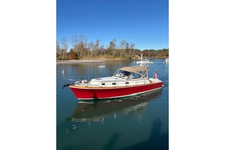 Slide: The Image of 1998 Grand Banks 38 Eastbay EX boat cruising on a serene lake under clear blue skies. - 31