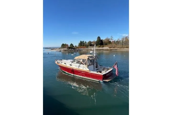 Slide: The Image of 1998 Grand Banks 38 Eastbay EX boat cruising on a serene waterway under a clear blue sky. - 36