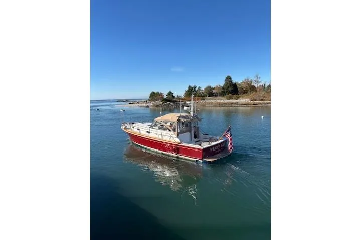 Slide: The Image of 1998 Grand Banks 38 Eastbay EX cruising on a serene waterway under a clear blue sky. - 37