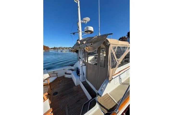 Slide: The Image of 1998 Grand Banks 38 Eastbay EX yacht with canopy, docked by a scenic waterfront. - 8