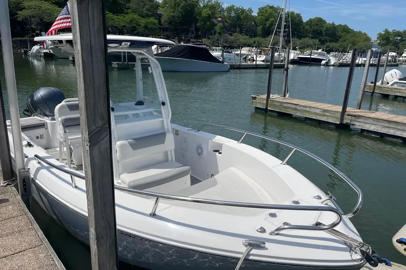 Slide: The Image of 2018 Everglades 230 Center Console boat docked at a marina with scenic background. - 2