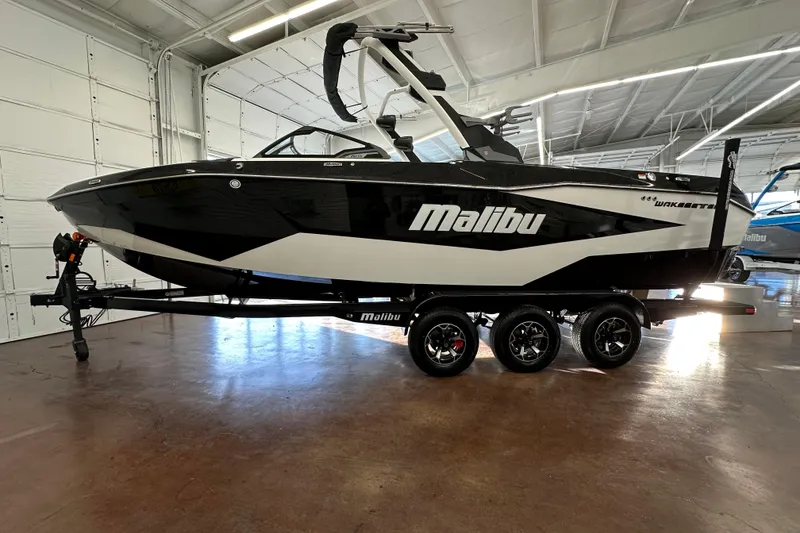 The Image of 2026 Malibu Wakesetter 25 LSV boat in showroom, black and white design, on trailer. - 8