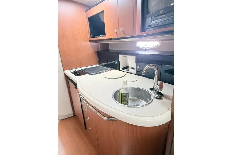 Slide: The Image of 2002 Chaparral 350 Signature yacht kitchen with sink, stove, and wooden cabinetry. - 19