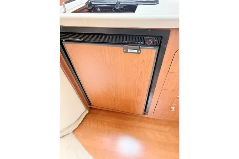 Slide: The Image of 2002 Chaparral 350 Signature boat interior with wooden cabinetry and compact refrigerator. - 23