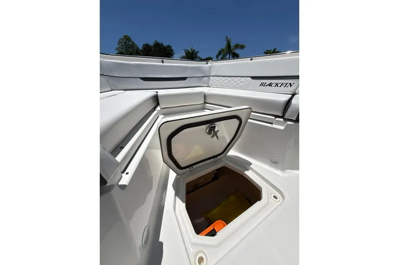 Slide: The Image of 2022 Blackfin 252 CC boat storage compartment open under clear blue sky. - 12