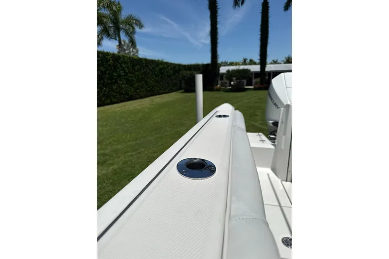 Slide: The Image of 2022 Blackfin 252 CC boat detail with lush greenery and clear sky background. - 15