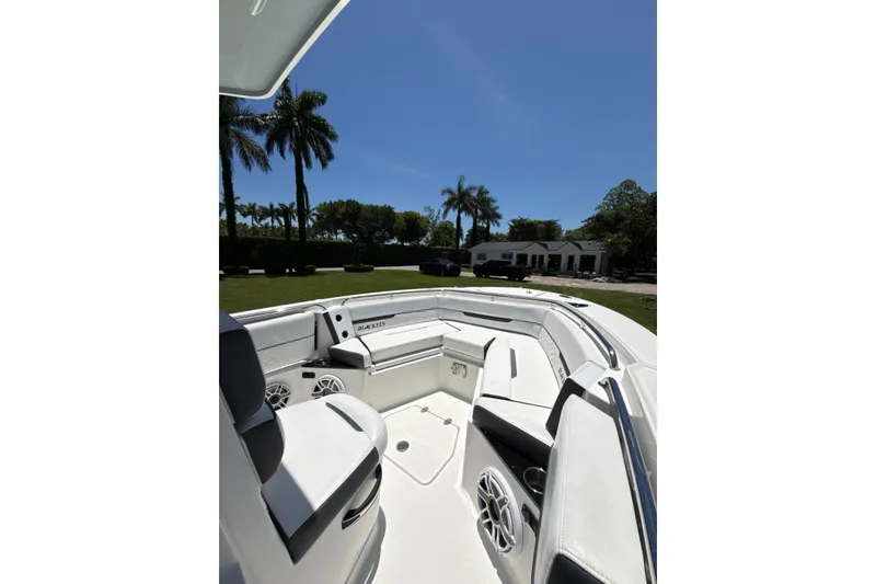 Slide: The Image of 2022 Blackfin 252 CC boat interior with seating, speakers, and palm trees in the background. - 17