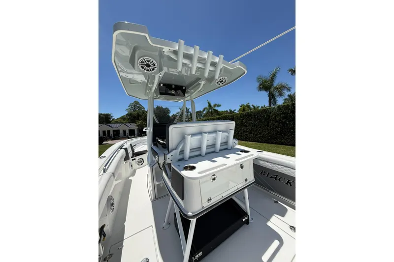 Slide: The Image of 2022 Blackfin 252 CC boat interior with rod holders and storage, under clear blue sky. - 27