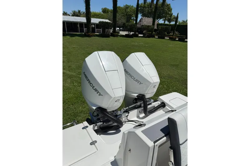 Slide: The Image of Twin Mercury outboard engines on a 2022 Blackfin 252 CC boat, parked on grass. - 30