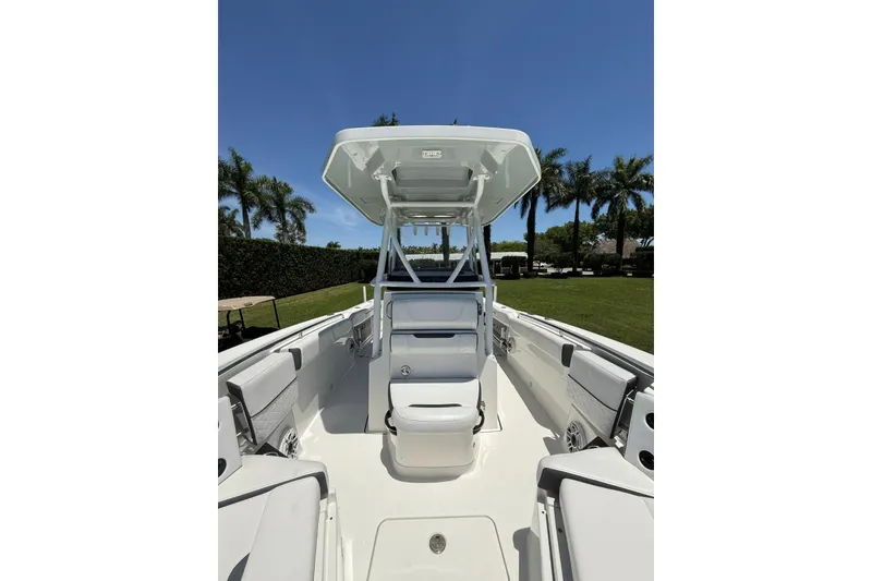 Slide: The Image of 2022 Blackfin 252 CC boat interior with seating, under clear blue sky and palm trees. - 36