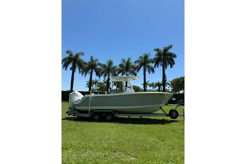 Slide: The Image of 2022 Blackfin 252 CC boat on trailer, parked on grass with palm trees in background. - 4