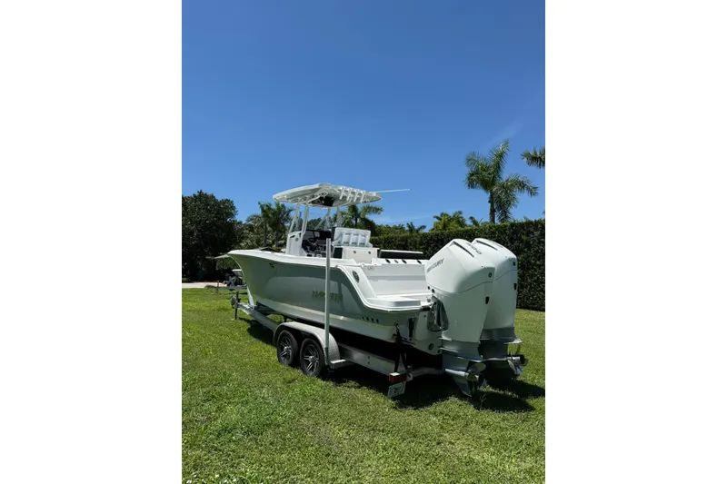 Slide: The Image of 2022 Blackfin 252 CC boat on trailer, parked on grass under clear blue sky. - 5
