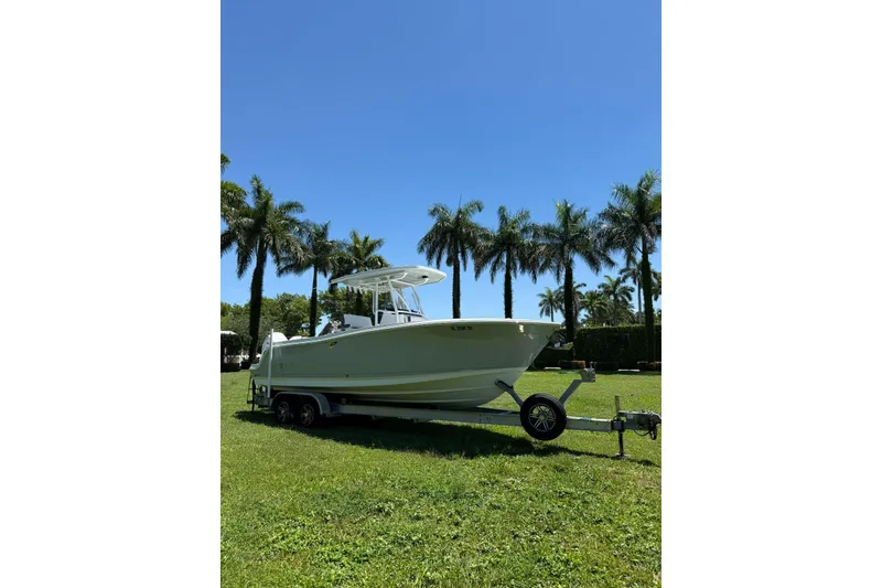 Slide: The Image of 2022 Blackfin 252 CC boat on trailer, parked on grass with palm trees in background. - 6