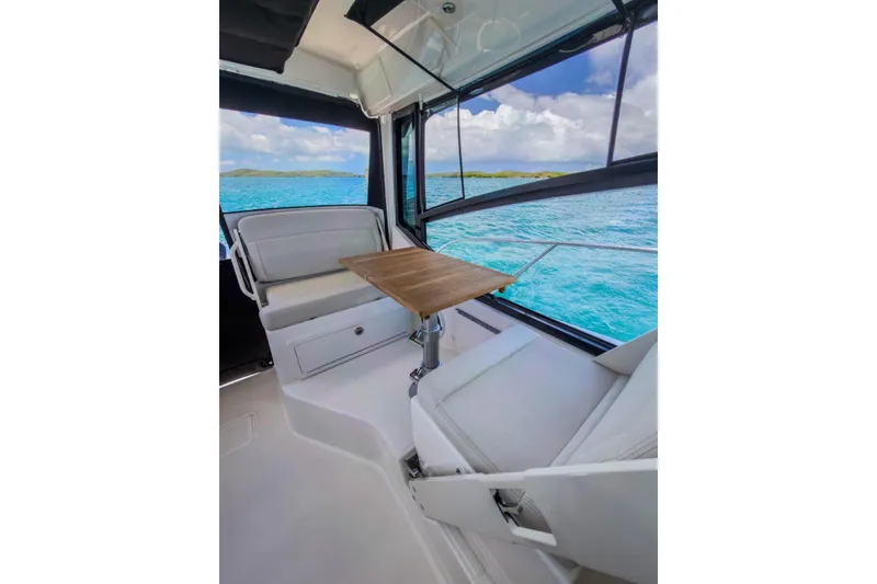 Slide: The Image of 2024 Boston Whaler 325 Conquest interior with seating and table, overlooking ocean view. - 12