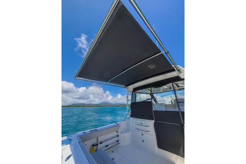 Slide: The Image of 2024 Boston Whaler 325 Conquest boat with canopy, ocean view, and clear blue sky. - 6