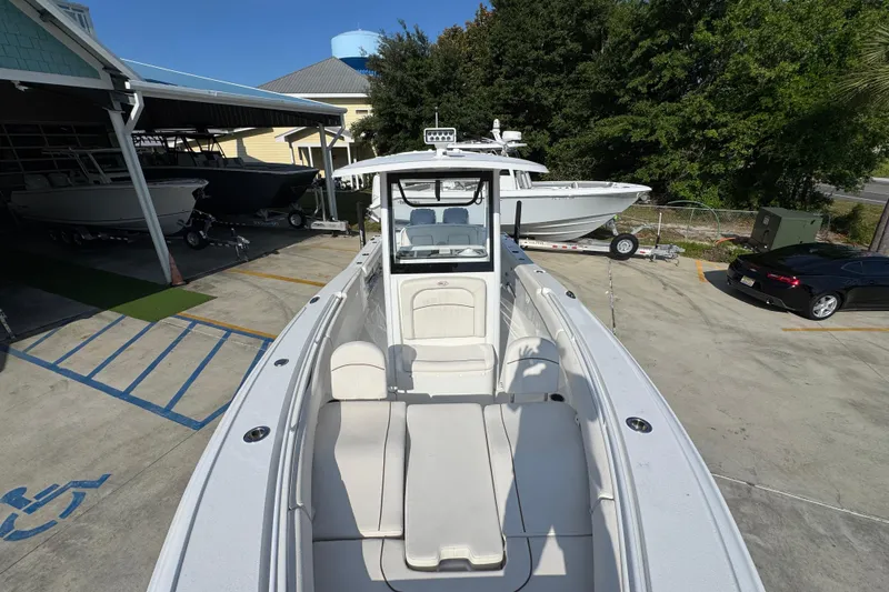 Slide: The Image of 2022 Sea Hunt Ultra 275 SE boat in a marina, showcasing sleek design and spacious seating. - 18