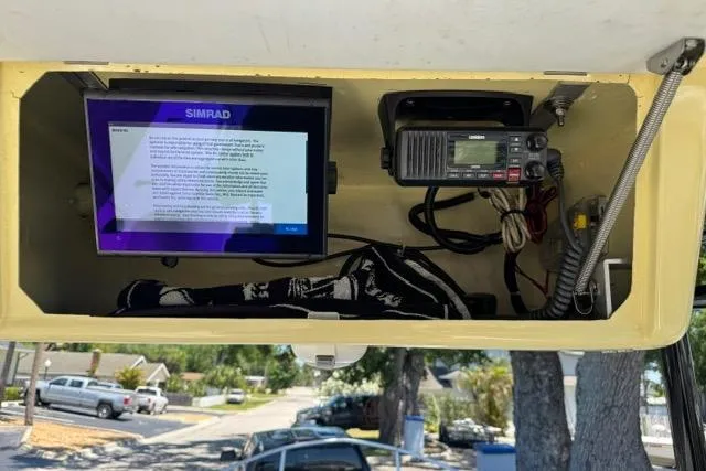 Slide: The Image of 1987 Mako 232 Center Console with Simrad display and radio equipment in overhead compartment. - 15