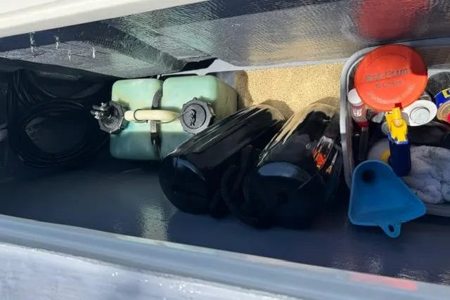 Slide: The Image of Storage compartment of a 1987 Mako 232 Center Console with fuel tanks and boating supplies. - 18