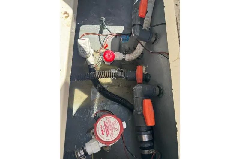 Slide: The Image of 1987 Mako 232 Center Console bilge area with pumps and hoses. - 20