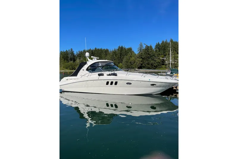 Slide: The Image of 2006 Sea Ray 38 Sundancer yacht docked on calm water, surrounded by lush greenery. - 1