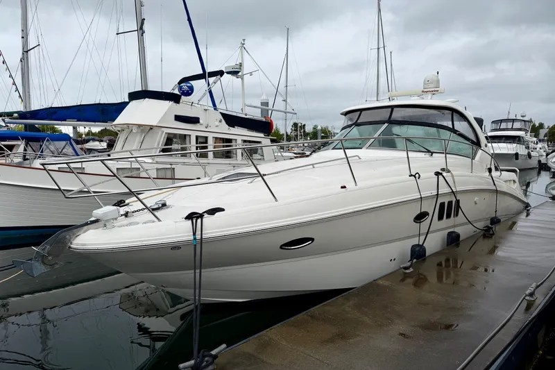 Slide: The Image of 2006 Sea Ray 38 Sundancer yacht docked at a marina on a cloudy day. - 2