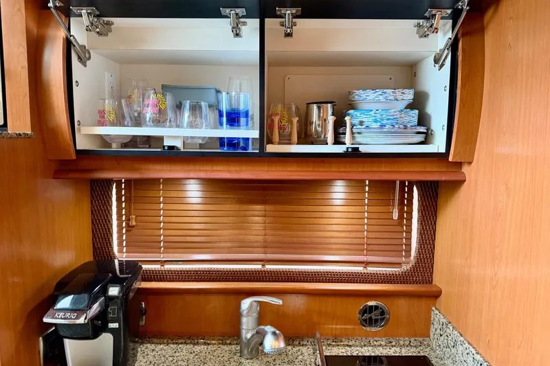 Slide: The Image of 2006 Sea Ray 38 Sundancer kitchen with open cabinets, glassware, and plates. - 22