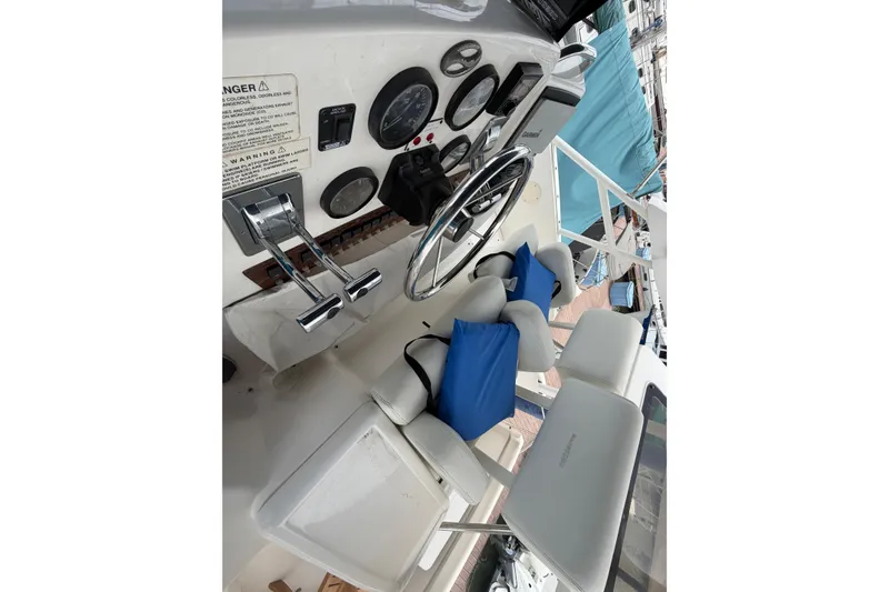 Slide: The Image of 1999 Silverton 352 Motor Yacht helm with steering wheel, gauges, and cushioned seating. - 12