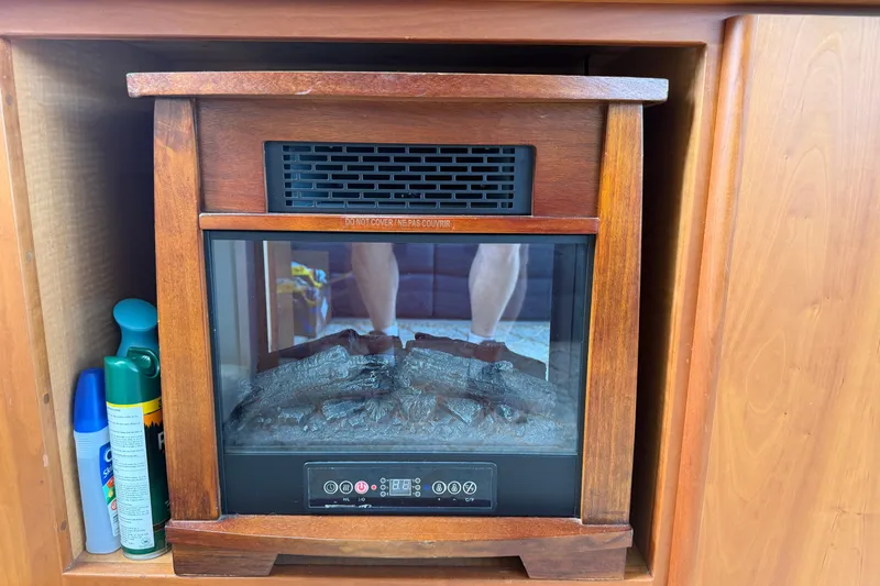 Slide: The Image of Wooden cabinet with electric fireplace and aerosol cans, inside a 1999 Silverton 352 Motor Yacht. - 31
