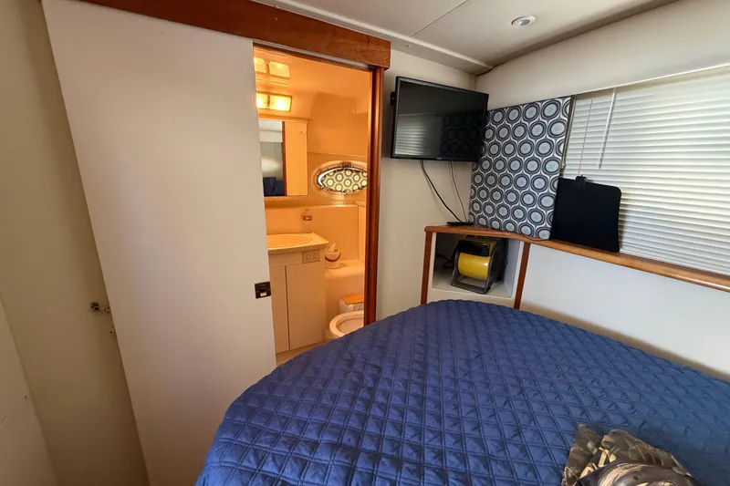 Slide: The Image of 1999 Silverton 352 Motor Yacht interior with bedroom, bathroom, TV, and blue bedding. - 40