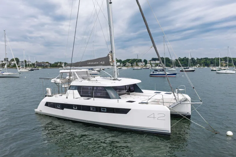 The Image of 2022 Leopard 42 catamaran anchored in a scenic harbor with other boats. - 1