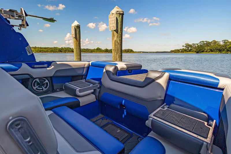 Slide: The Image of Interior of a 2017 Malibu M235 boat with blue and gray seating by the water. - 12
