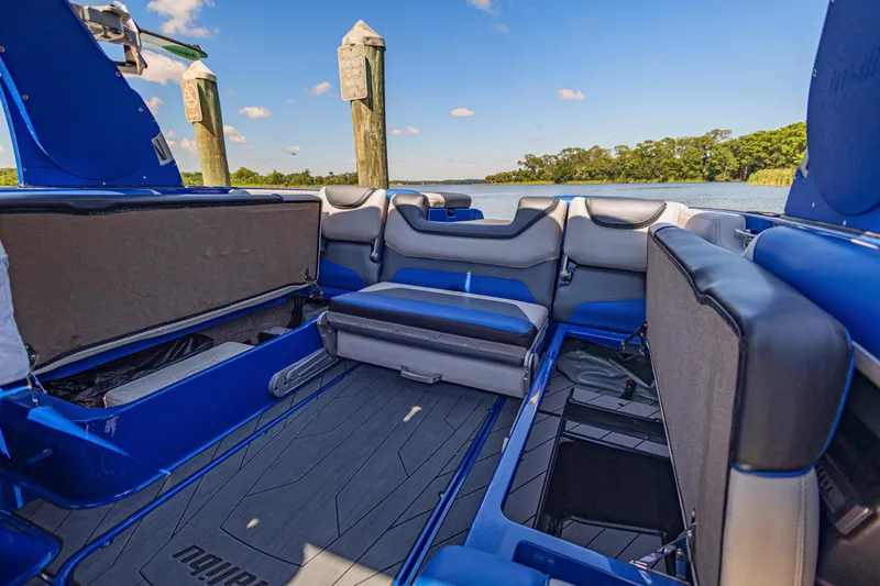 Slide: The Image of Interior of a 2017 Malibu M235 boat with blue and gray seating, docked by a scenic lake. - 15