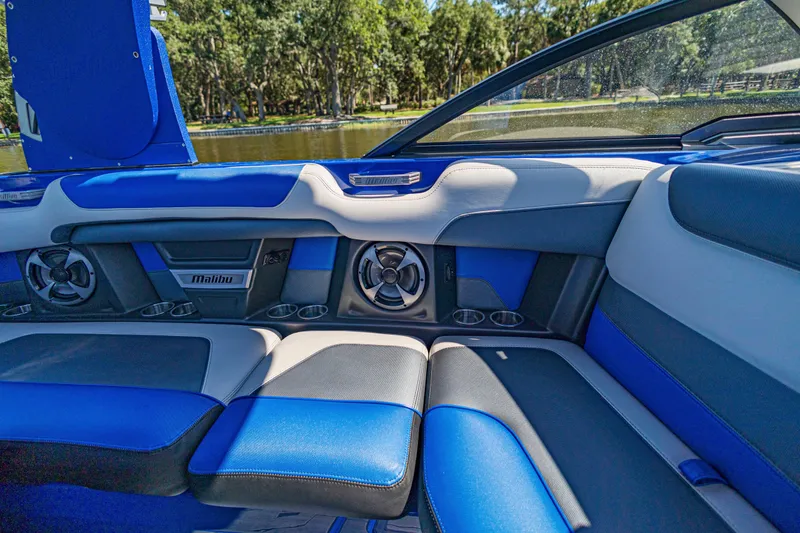 Slide: The Image of Interior of 2017 Malibu M235 boat with blue and gray seating, cup holders, and speakers. - 19