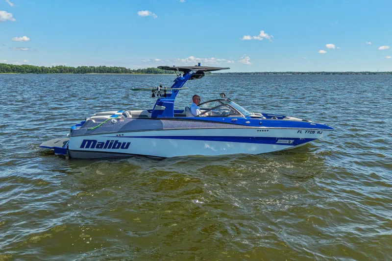 Slide: The Image of 2017 Malibu M235 boat cruising on a sunny lake. - 2