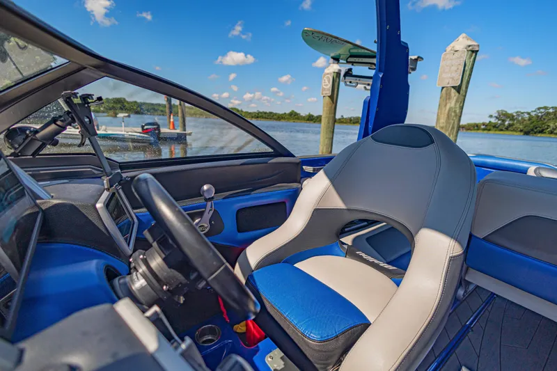 Slide: The Image of Interior of a 2017 Malibu M235 boat with blue and gray seating by the water. - 24