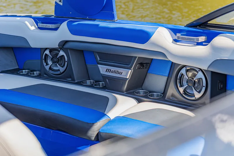 Slide: The Image of 2017 Malibu M235 boat interior with blue and white seating, speakers, and cup holders. - 27