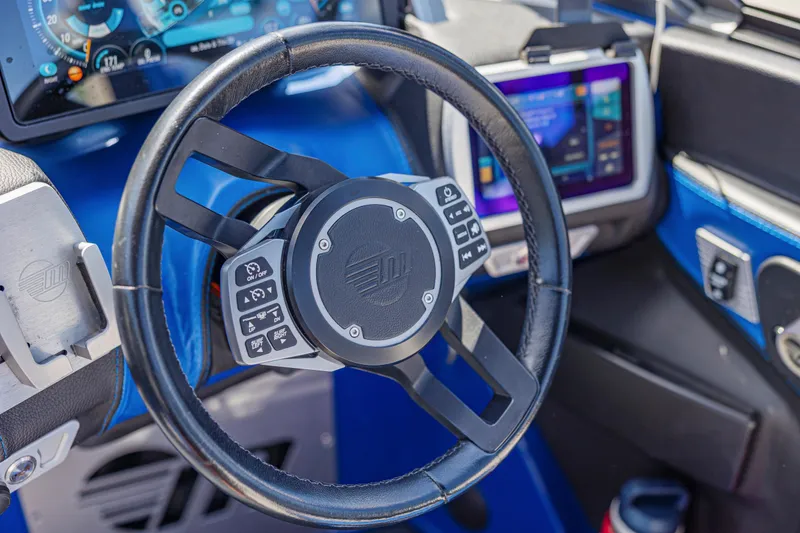 Slide: The Image of Steering wheel and dashboard of a 2017 Malibu M235 boat, featuring modern controls and displays. - 28