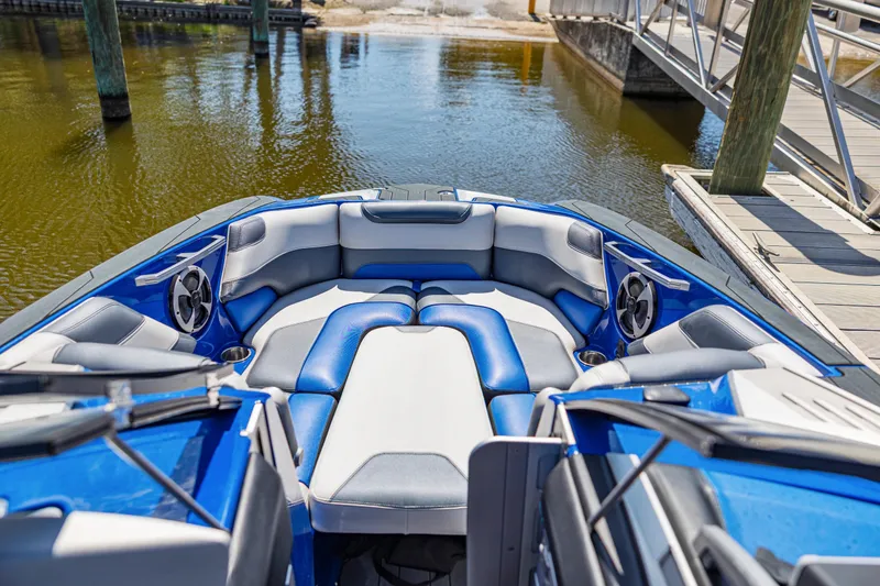 Slide: The Image of 2017 Malibu M235 boat interior with blue and white seating, docked by a wooden pier. - 29