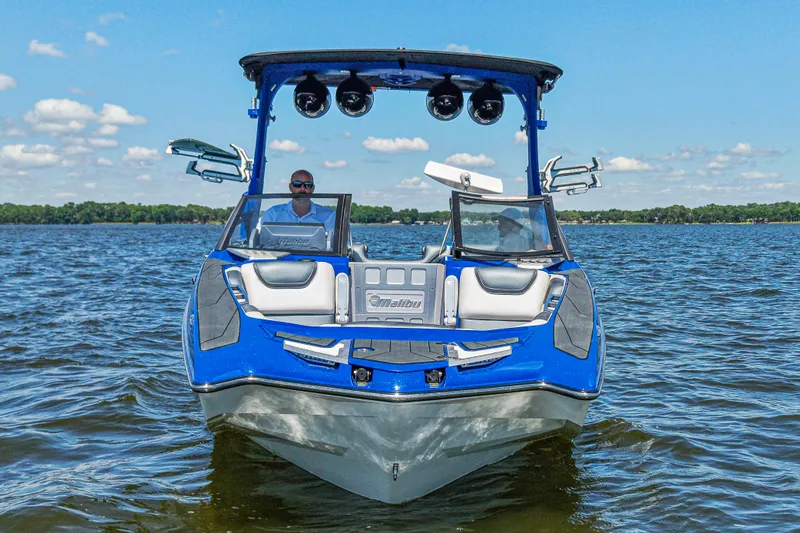 Slide: The Image of 2017 Malibu M235 boat on a lake, featuring a sleek blue design and modern amenities. - 3