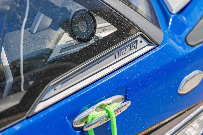 Slide: The Image of Close-up of a blue 2017 Malibu M235 boat with visible logo and green rope. - 30